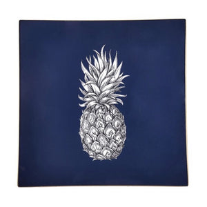 An artisanal, decorative glass valet tray with a pineapple illustration on a navy background finished with an 18kt gold leaf edging