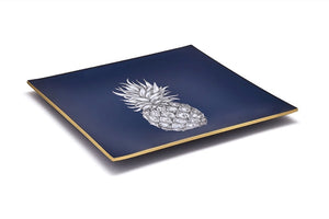 An artisanal, decorative glass valet tray with a pineapple illustration on a navy background finished with an 18kt gold leaf edging