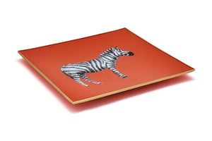 An artisanal, decorative glass valet tray with a zebra illustration on an orange background finished with an 18kt gold leaf edging