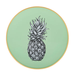 An artisanal, decorative glass round tray with a pineapple illustration on a pale sage green background finished with an 18kt gold leaf edging