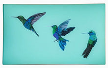 Load image into Gallery viewer, A decorative glass valet tray with three hummingbird illustrations on an aqua background and finished with an 18kt gold leaf edging